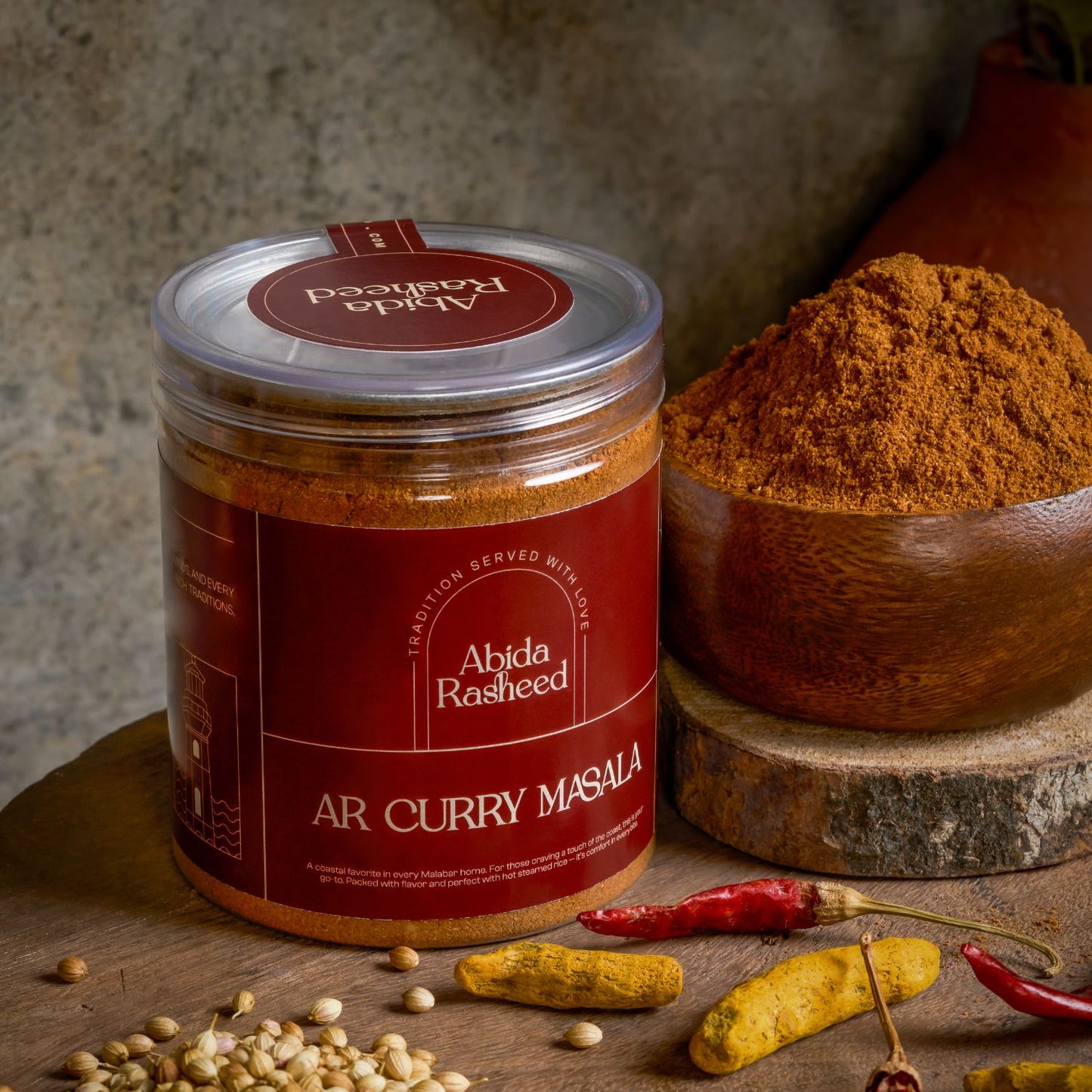 Jar of Abida Rasheed AR Curry Masala with spices and chilies on a wooden surface
