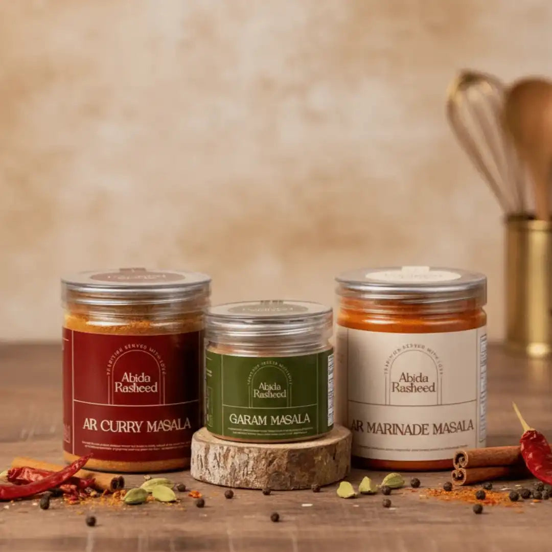 Jars of Abida Rasheed Garam Masala displayed with a bowl of the hand-roasted spice blend, with text emphasizing its traditional family recipe and lack of preservatives.